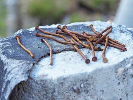old rusty curved nails lie in a pile on a concrete postの写真素材