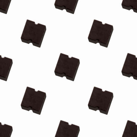 small chocolate bar on a light background. seamless pattern. Background image. Hard shadow. The view...