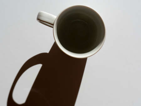 empty white mug on a light background. close-up, hard shadows