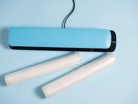 close-up of a blue vacuum packer on a bright blue background. Next to the packaging bags. A machine...