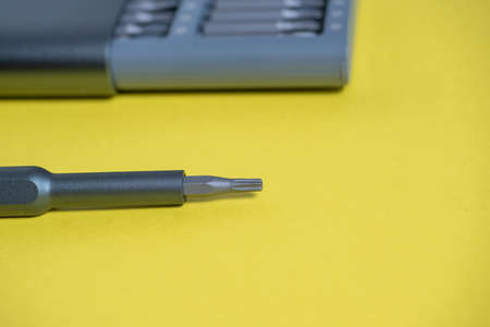 A set of screwdrivers with bits in a case on a yellow background. Tools for work. the screwdriver is next to the setの写真素材