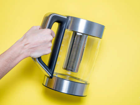 a woman holds in her hand a silver-colored electric metal kettle with various water heating modes on...