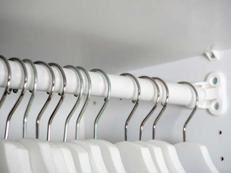 close-up of white wooden hangers in the closet. Selective focus on hooks. equipment for the homeの写真素材