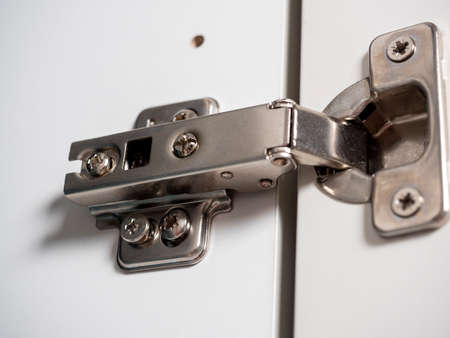 Furniture hinges for white wooden furniture door close-up.の写真素材