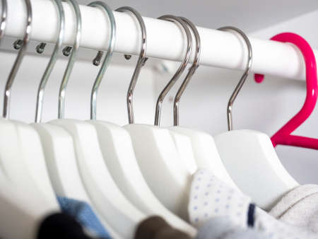 Hangers in the closet close-up with clothes. Among the whites, one is redの写真素材