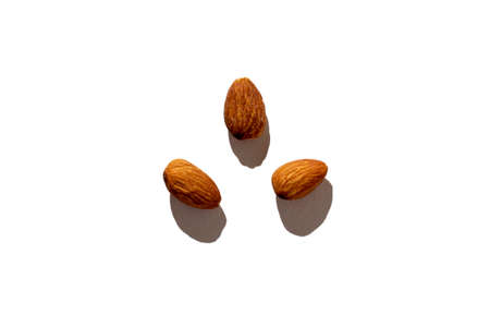 three whole almonds lie isolated on a white background. Hard shadows, top view, flat layの写真素材