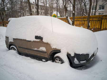 cars parked on the side of the road are covered with a thick layer of snow after a snowfall.の写真素材