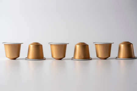 golden aluminum capsules with ground coffee for the coffee machine are displayed in a row on a white backgroundのeditorial素材