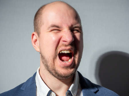 close-up portrait of a Caucasian man in a jacket who is shouting furiously. Aggression, challenge, emotion.のeditorial素材