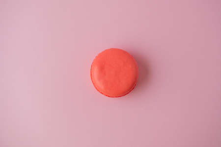 one macaroon cookie is orange on a pink paper background. Minimalism, delicious dessertの写真素材