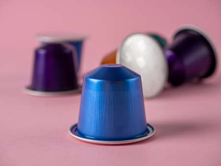 Colorful aluminum capsules with ground coffee on a paper rose background. Capsules for the coffee...