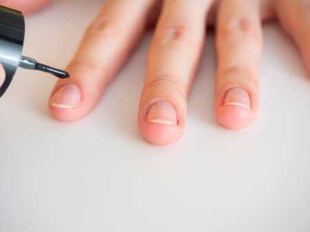 applying a colorless base to the nail. Manicure at homeの写真素材