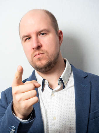 A middle-aged man in a jacket looks at the camera and points forward with his finger.のeditorial素材