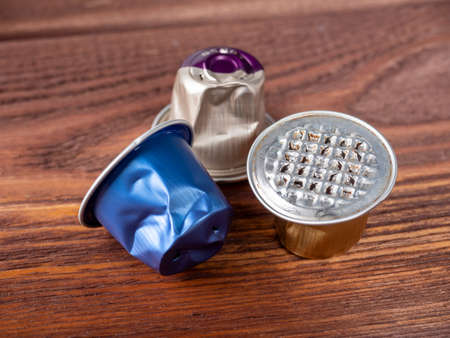 Several used aluminum capsules for the coffee machine lie on a brown wooden background. Concept of recyclable materialsのeditorial素材