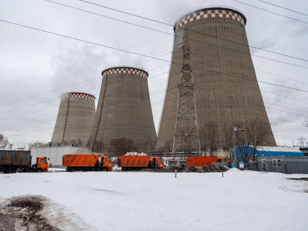 02/27/2021 Russia, Moscow. Harvesters loaded with snow stand in a row for processing snow. Behind them are the large pipes of the thermal power plantのeditorial素材
