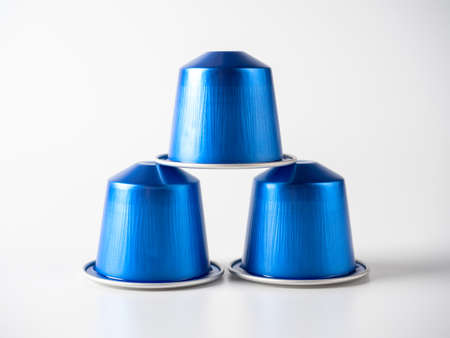 Aluminum capsules of blue color with ground coffee for coffee machines stand on a white background. Isolated objects, reflection. Pyramid of capsules.のeditorial素材