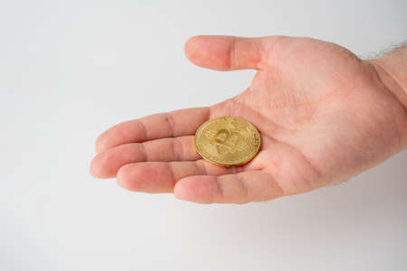 on the open male palm is a gold bitcoin. White background. Cryptocurrency Conceptのeditorial素材