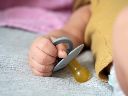 Close-up of a small child holding a pacifier with his hand