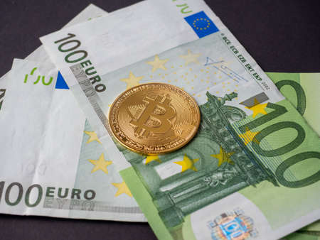Golden bitcoin is on the bills of one hundred euros. Black background. Side view. Cryptocurrency Conceptの写真素材