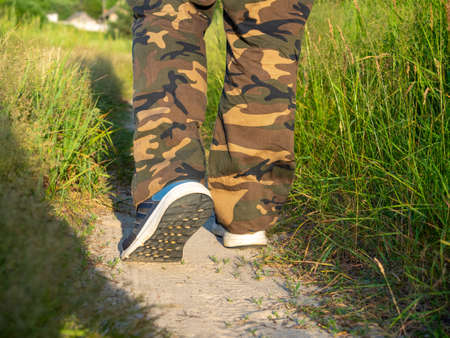 close-up of the legs of a man dressed in sneakers walking along a path in the forest. The concept of hiking, walking and a sporty lifestyle. rear viewの写真素材