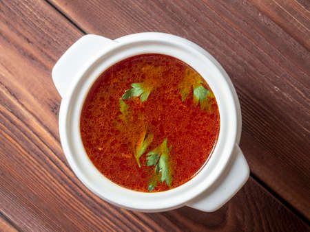 Close-up of soup borscht in a white ceramic soup bowl on a wooden background. Traditional soup for Russia and Ukraine. Greens float on top of the soup. Top view, flat layの写真素材