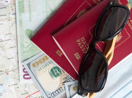 Two Russian passports are on the card and dollar and euro bills. On top of the passports are black sunglasses. The concept of tourism and travel. Top view, flat layの写真素材