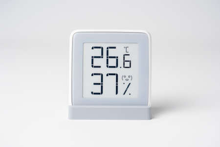 A home weather station standing on a white background is a modern device with a screen showing the temperature and humidity in the room. Front view. studio shotの写真素材