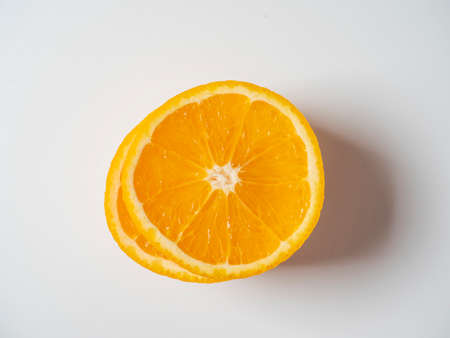 A close-up of an orange cut into slices lies on a white background. Delicious beautiful fruit full of vitamins. Studio shot. top view, flat layの写真素材