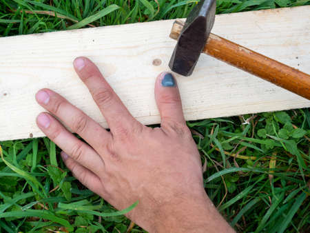 A close-up of a worker misses and hits the thumb of his hand. Hematoma, bruise, bruise. Grass at work. insurance. Top view, flat layの写真素材
