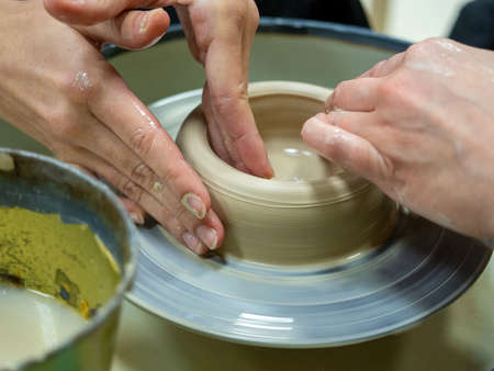 Close-up of people's hands making an object out of raw clay on a potter's wheel. Conducted master classes and workshops. Hobby, selective focusの写真素材