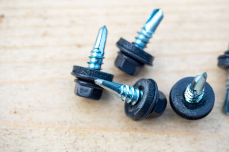 a bunch of roofing screws painted gray on a wooden background. Top view, flat layの写真素材
