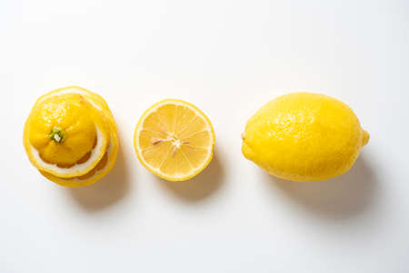 Close-up of a cut and whole lemon lying on a white background. isolated fruit. Sour yellow fruit full of vitamins. Top view, flat layの写真素材