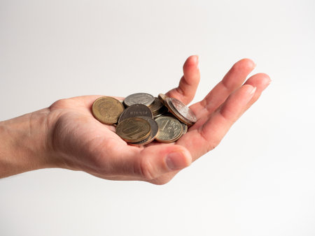 Close-up of a palm with a bunch of coins on a white background. Rubles, the concept of an economic crisis and the depreciation of money. Poverty, side viewの写真素材
