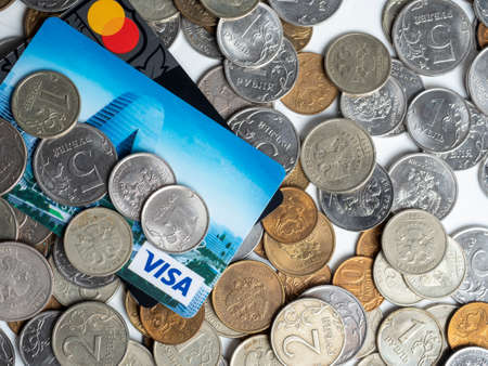 01/03/2022 Russia, Moscow. Close-up of the tinkoff and Sberbank bank cards lie on a background of coins. The concept of e-commerce, banking, finance. Mastercard, Visaのeditorial素材