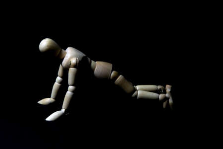 wood manikins pushups stance on black background., low-key technique.の写真素材