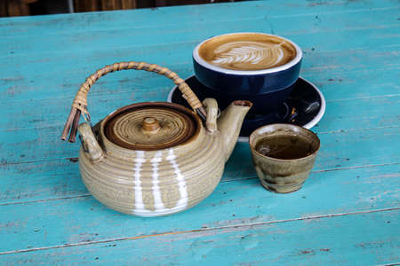 Hot art Latte Coffee and tea in a cup on blue wooden table.の写真素材