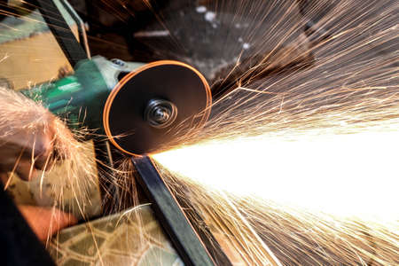  Worker cutting metal with grinder. Sparks while grinding iron