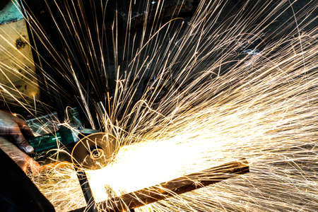  Worker cutting metal with grinder. Sparks while grinding ironの写真素材