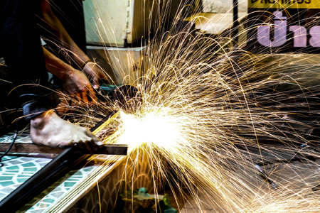  Worker cutting metal with grinder. Sparks while grinding iron