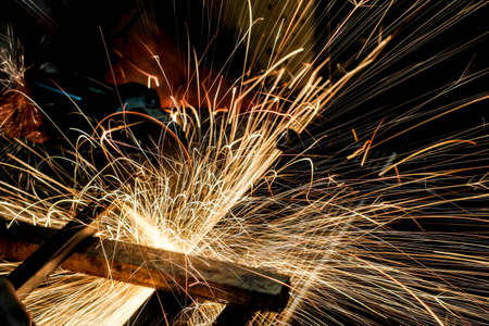  Worker cutting metal with grinder. Sparks while grinding ironの写真素材