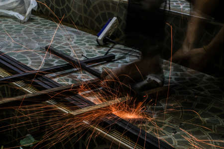  Worker cutting metal with grinder. Sparks while grinding ironの写真素材