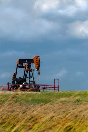 A single oil rig on the windly prairies, with stormy skies.のeditorial素材