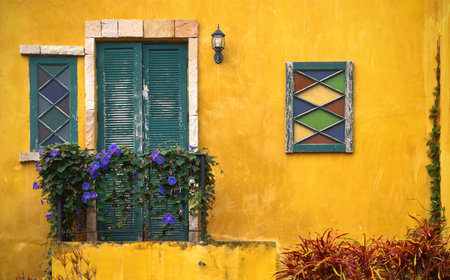 Yellow vintage facade and balcony with colorful plant, old green door and colorful window, vintage...