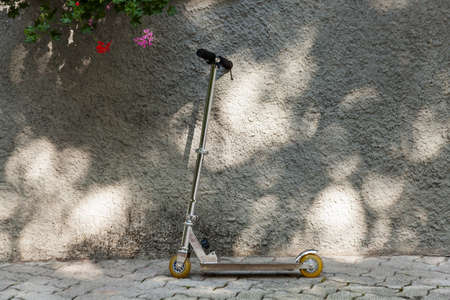 Kick scooter resting on the wall in the summer sunの写真素材