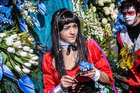 NICE - FRANCE - March 01, 2014: Carnival of Nice, Flowers' battle. Young woman with a blue flowerのeditorial素材