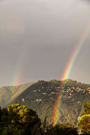 Double rainbow over the mountain overlooking Como. City of Brunate in summertime. Como Lake. Italyの写真素材