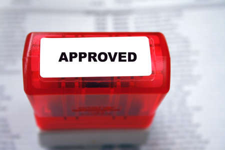 Stamp with approved sitting on papers for the background