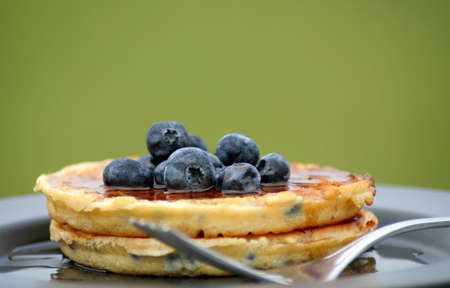 
blueberry waffles on a plate with fork and fresh blueberries.の写真素材