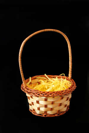 an easter basket full of yellow easter grass isolated on a black background done in a vertical format.の写真素材
