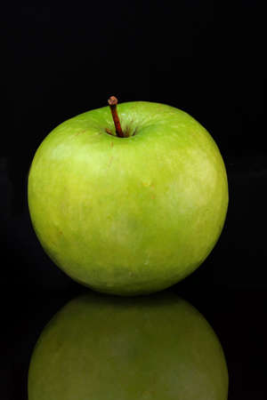 Green apple isolated on a black bacground with a reflection.の写真素材